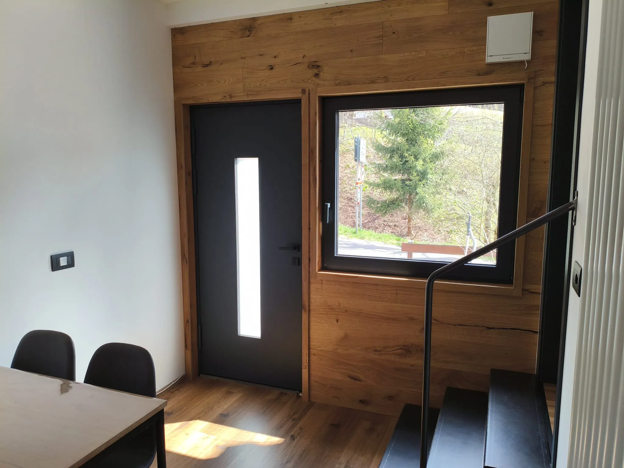 Ingresso interno con boiserie in legno di rovere e finestra sul giardino