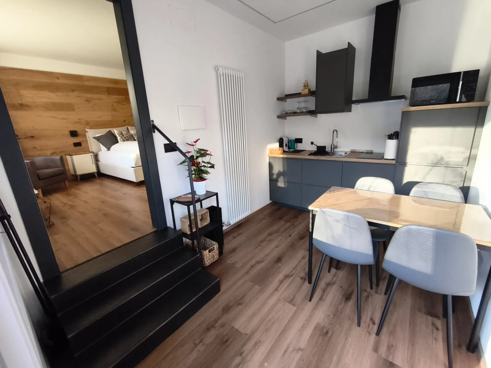 Zona giorno con cucina antracite, tavolo, scala interna e dettagli in legno
